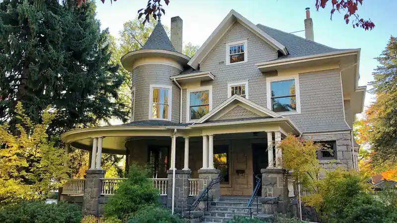 A restored early-1900s character home with a turret and wraparound porch